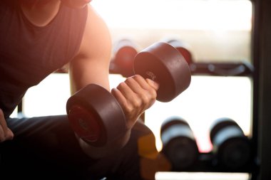 Dumbbell egzersiz spor salonunda tutan adam el. Spor salonu arka planda siyah ağırlıklar Fitness kas vücut ile ayarlayın. egzersiz ve sağlıklı yaşam konsepti.