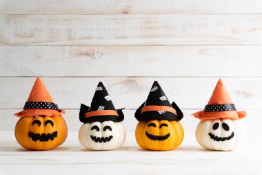 Cadı şapkası sopası ile beyaz ahşap borad arka plan üzerinde beyaz ve sarı hayalet balkabağı. Cadılar Bayramı kavramı.