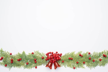 Noel ve yeni yıl kompozisyon. Beyaz arka plan üzerinde çam dalları, çam kozalakları, kırmızı meyveler ve çan üstten görünüm.