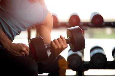 Dumbbell egzersiz spor salonunda tutan adam el. Spor salonu arka planda siyah ağırlıklar Fitness kas vücut ile ayarlayın. egzersiz ve sağlıklı yaşam konsepti.
