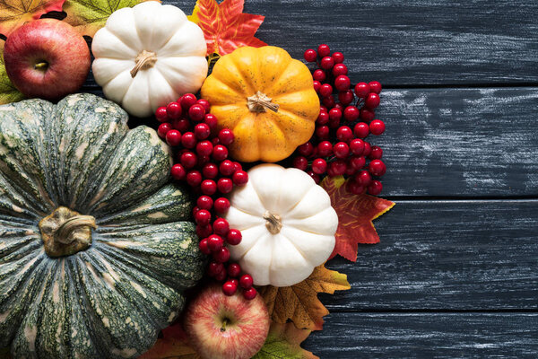 Вид сверху на листья картона Autumn с тыквой и красными ягодами на старом деревянном фоне. Концепция Дня благодарения
.