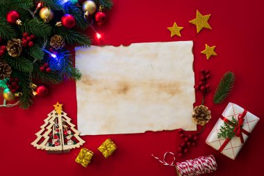 Noel arka plan kavramı. Noel hediye kutusu eski kağıt çam dalları, çam kozalakları, kırmızı meyveler ve bell ile üstten görünüm kırmızı zemin üzerine.