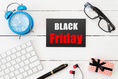 Siyah Cuma satış metin ile hediye kutusu, kırmızı ve siyah bir etiketteki gözlük, kulaklık kalem ve ve çalar saat ve beyaz ahşap masa arka plan üzerinde. Alışveriş kavramı.