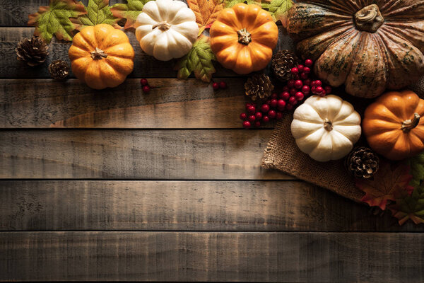 Вид сверху на листья картона Autumn с тыквой и красными ягодами на старом деревянном фоне. Концепция Дня благодарения
.