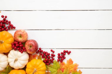 Yukarıdan Sonbahar akçaağaç balkabağı ve kırmızı çilek ile beyaz ahşap arka plan üzerinde bırakır. Şükran günü kavramı.