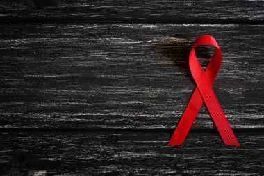 Tatlı kırmızı kurdele farkındalık Dünya AIDS Günü kampanyası için siyah ahşap masa arka plan üzerinde.
