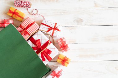 Noel ve yeni yıl kompozisyon. İleti etiketi ile hediye kutusu ve kırmızı alışveriş çantası üstten görünüm ahşap beyaz zemin üzerine.