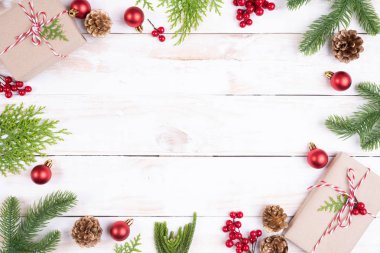 Noel arka plan kavramı. Noel hediye kutusu çam dalları, çam kozalakları, kırmızı meyveler ve bell ile üstten görünüm Beyaz ahşap masa arka plan üzerinde.