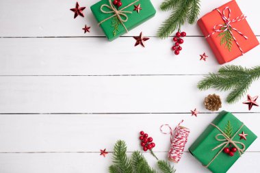 Noel arka plan kavramı. Yeşil ve kırmızı hediye kutusu ile Ladin dalları, çam kozalakları, kırmızı meyveler Noel görünümünü üst ve beyaz ahşap arka plan üzerinde çan.