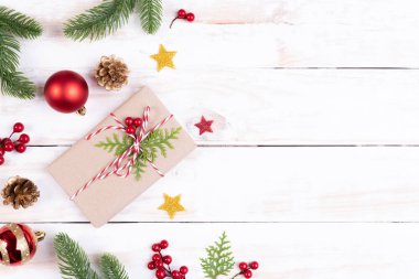Noel arka plan kavramı. Noel hediye kutusu çam dalları, çam kozalakları, kırmızı meyveler ve bell ile üstten görünüm Beyaz ahşap masa arka plan üzerinde.