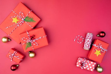 Noel arka plan kavramı. Noel hediye kutu kırmızı topları çam dalları, çam kozalakları, kırmızı meyveler ve bell ile üstten görünüm kırmızı zemin üzerine.