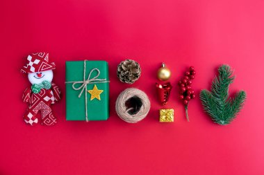 Noel arka plan kavramı. Noel green Hediyelik kutu kardan adam çam dalları, çam kozalakları, kırmızı meyveler ve bell ile üstten görünüm kırmızı zemin üzerine.