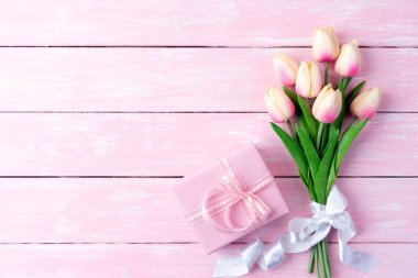 Sevgililer günü ve aşk kavramı. Hediye kutusu ve lale ile şerit pembe pastel ahşap arka plan üzerinde pembe kağıt kalpler.