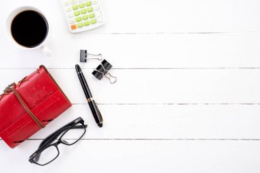Beyaz ahşap ofis resepsiyon masaları boş defter, hesap makinesi, kahve fincanı ve diğer ofis malzemeleri. Üstten görünüm kopya alanı, düz ile yatıyordu.