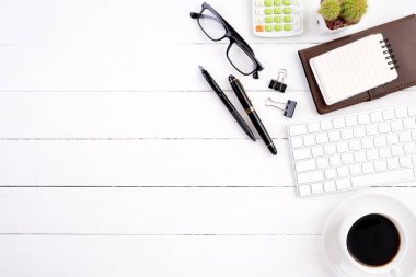 Beyaz ahşap ofis resepsiyon masaları boş dizüstü bilgisayar, bilgisayar klavye hesap makinesi, kahve fincanı ve diğer ofis malzemeleri. Üstten görünüm kopya alanı, düz ile yatıyordu.