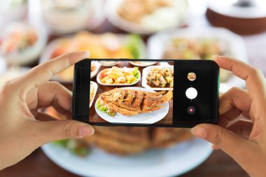 Restoranda yemek smartphone ile bir fotoğraf çekici kadın.