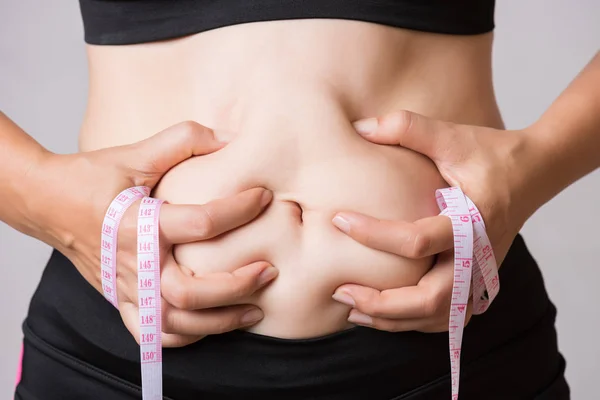 測定テープと過度のおなかの脂肪を持つ脂肪女性の手 女性ダイエット腹を軽減しシェイプ アップ腹筋を鍛えて健康的なライフ スタイルのコンセプト — ストック写真