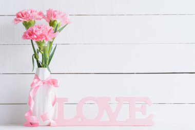 Sevgililer günü ve aşk kavramı. Ahşap harflerle kelime beyaz zemin üzerine yazılmış aşk şekillendirme vazoda pembe karanfil çiçek.
