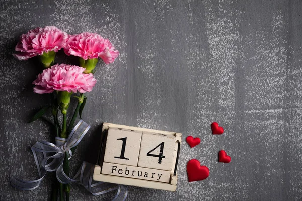 情人节和爱情的概念 粉红色康乃馨花与2月14日文本木块日历和红色心脏和灰色木制背景 — 图库照片
