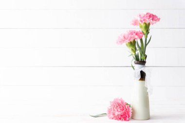 Sevgililer günü ve aşk kavramı. Beyaz ahşap zemin üzerinde vazoda pembe karanfil çiçek.
