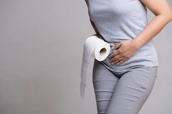 Woman hand holding her crotch lower abdomen and tissue or toilet paper roll. Disorder, Diarrhea, incontinence. Healthcare concept. — Stock Image Woman Hand Holding Her Crotch Lower Abdomen Tissue Toilet Paper Stock Image