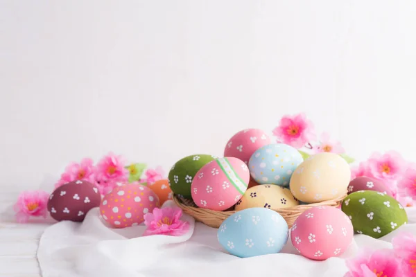 Frohe Ostern! Bunte Ostereier im Nest mit Blüten und Blüten — Stockfoto
