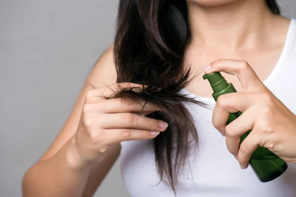 Healthy concept. Woman hand holding damaged long hair with Oil H