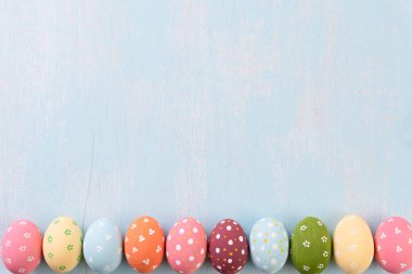 Mutlu Paskalyalar! Parlak mavi ahşap arka plan üzerinde satır Paskalya yumurtaları.