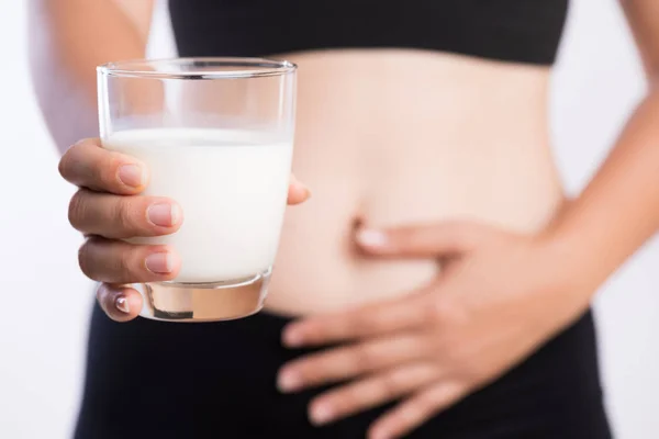 Woman hand holding glass of milk having bad stomach ache because