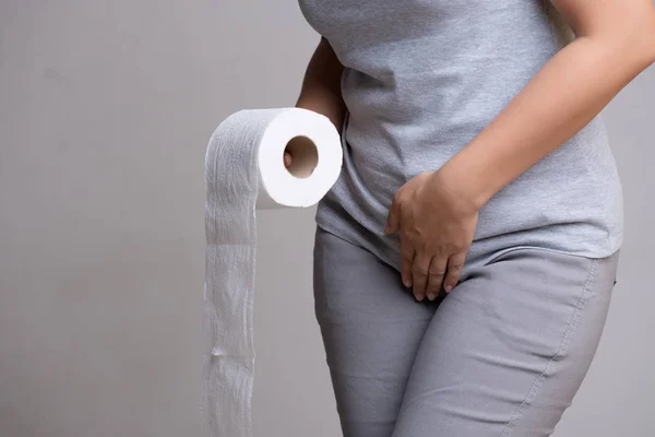 Женщина держит свою промежность ниже живота и ткани или туалета — стоковое фото