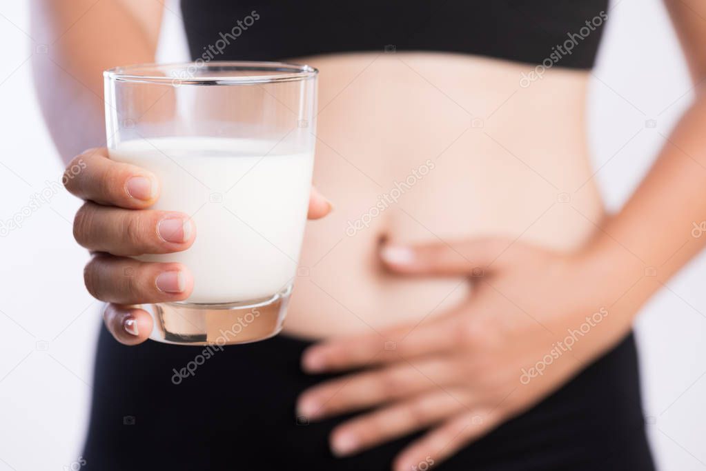 Woman hand holding glass of milk having bad stomach ache because