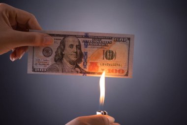 Kadın el ele tutuşmuş, yanan dolar parası.