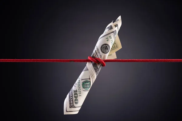 American dollar tied up in red rope knot on dark background Royalty Free Stock Photos