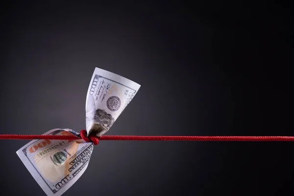 American dollar tied up in red rope knot on dark background Royalty Free Stock Images