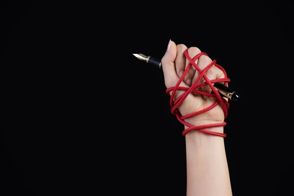 Woman hand with black pen tied with red rope, depicting the idea
