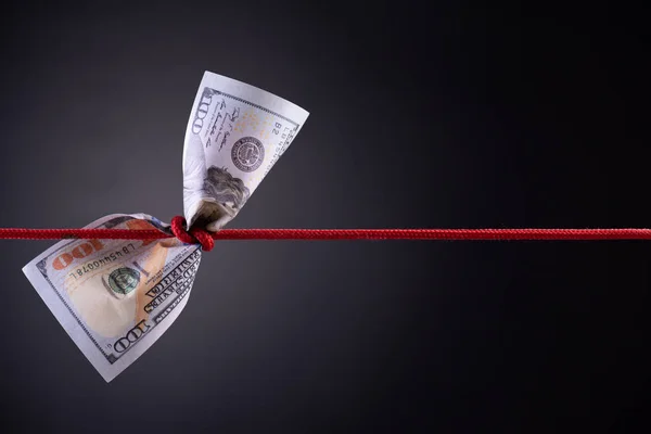 American dollar tied up in red rope knot on dark background with copy space. business finances, savings and bankruptcy concept. Stock Image