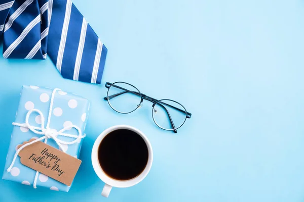 Conceito feliz do dia dos pais. Vista superior de gravata azul, bela caixa de presente, caneca de café, óculos com texto AMOR DAD em fundo pastel azul brilhante . — Fotografia de Stock