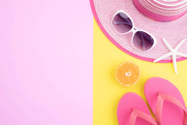 Accesorios de playa cámara de película retro, gafas de sol, chancla estrella de mar sombrero de playa y concha de mar sobre fondo rosa y amarillo para vacaciones de verano y el concepto de vacaciones . — Foto de Stock