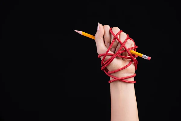 Woman hand with yellow pencil tied with red rope, depicting the idea of freedom of the press or expression on dark background. World press freedom and international human rights day concept. — Stock Photo, Image