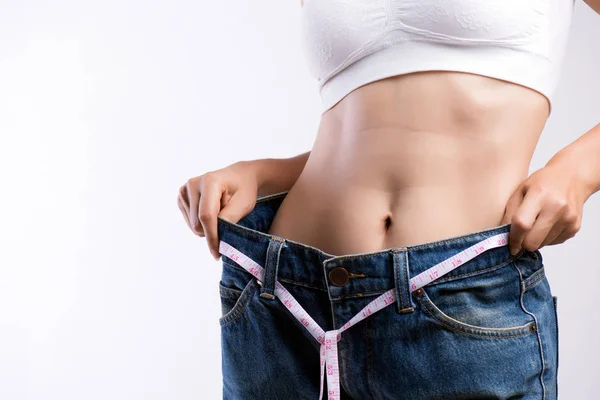 Acercamiento mujer joven delgada que mide su cintura delgada con una cinta métrica. Cuidado de la salud y la mujer dieta concepto de estilo de vida para reducir el vientre y formar el músculo del estómago saludable . —  Fotos de Stock