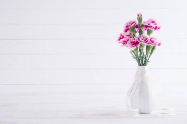 Sevgililer günü ve aşk kavramı. Beyaz ahşap zemin üzerinde vazoda pembe karanfil çiçek.