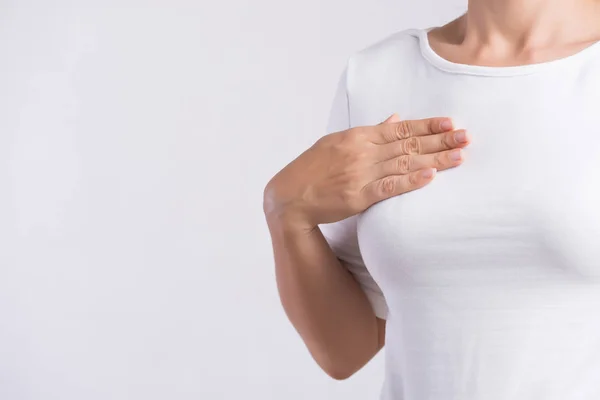 Mano de mujer revisando bultos en su pecho en busca de signos de cáncer de mama sobre fondo gris. Concepto sanitario. — Foto de Stock