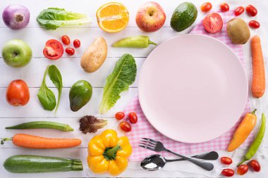 Sağlıklı yaşam tarzı ve gıda konsepti. Beyaz ahşap arka planda boş pembe pastel plaka ile taze sebze, meyve, otlar ve baharatlar üst görünümü.