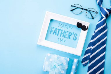 Mutlu babalar günü kavramı. Mavi kravat üst görünümü, güzel hediye kutusu, parlak mavi pastel arka plan üzerinde Mutlu babalar günü metin ile beyaz resim çerçevesi. Düz yatıyordu.