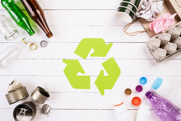 Top view of Different garbage materials with recycling symbol on white wooden table background. Recycle, World Environment Day and Eco concept