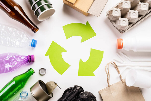 Top view of Different garbage materials with recycling symbol on white wooden table background. Recycle, World Environment Day and Eco concept