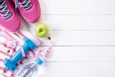 Sağlıklı yaşam tarzı, gıda ve spor konsepti. Atlet ekipmanının üst görünümü ağırlık ölçeği ölçüm bandı mavi dumbbell, spor su şişeleri, Beyaz ahşap arka planda meyve ve sebzeler.