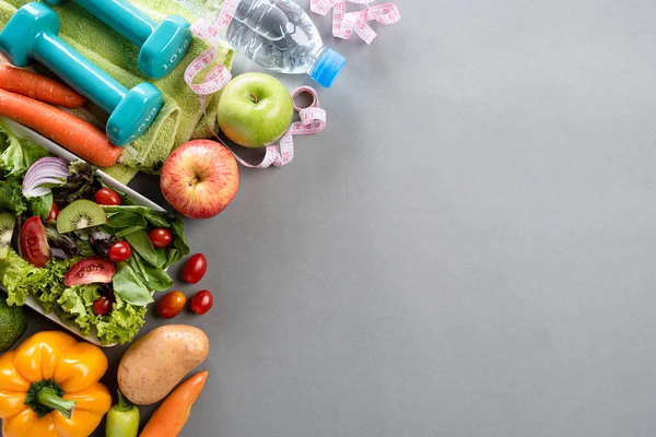 Estilo de vida saludable, comida y concepto deportivo. Vista superior del equipo del atleta Peso Escala cinta métrica mancuerna verde, deporte botellas de agua, frutas y verduras sobre fondo gris . — Foto de Stock