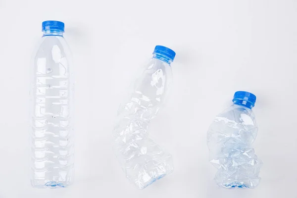 Draufsicht auf verschiedene leere Plastikwasserflaschen von voll bis zerkleinert auf weißem Hintergrund. Recycling, Weltumwelttag und Öko-Konzept — Stockfoto