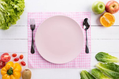 Sağlıklı yaşam tarzı ve gıda konsepti. Beyaz ahşap arka planda boş pembe pastel plaka ile taze sebze, meyve, otlar ve baharatlar üst görünümü.